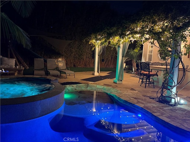 pool at twilight with a patio area and a pool with connected hot tub