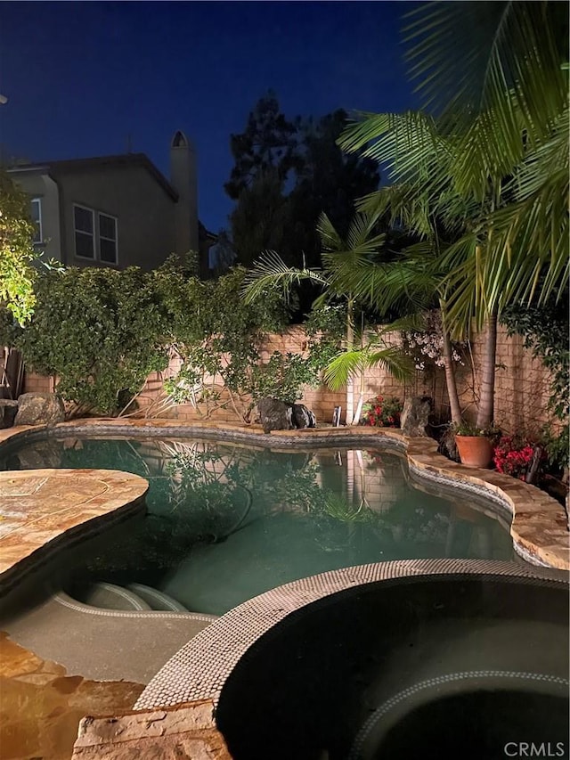 pool at twilight with a fenced in pool and a fenced backyard