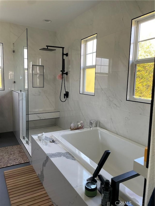 full bath with tile walls, a shower stall, and a bath