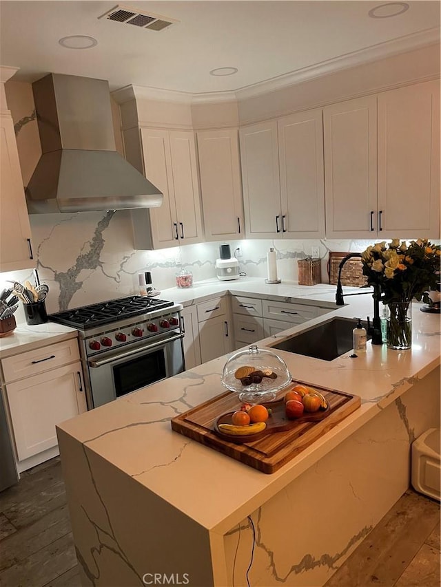 kitchen featuring visible vents, white cabinets, dark wood finished floors, wall chimney exhaust hood, and high end stainless steel range