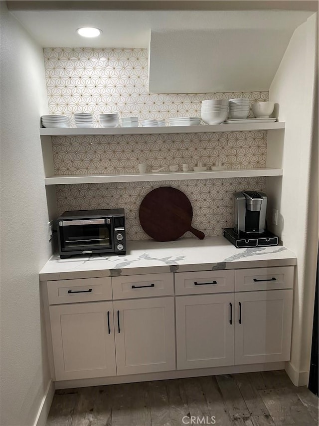 bar with baseboards, a toaster, light wood finished floors, and decorative backsplash