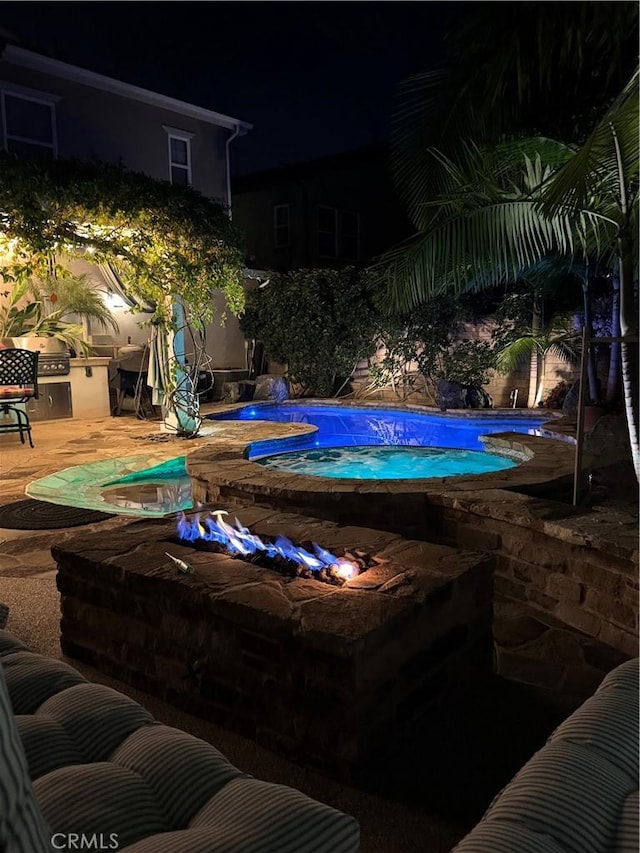 pool at twilight featuring an outdoor pool and an outdoor kitchen