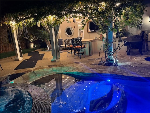 view of swimming pool featuring a pool with connected hot tub and a patio