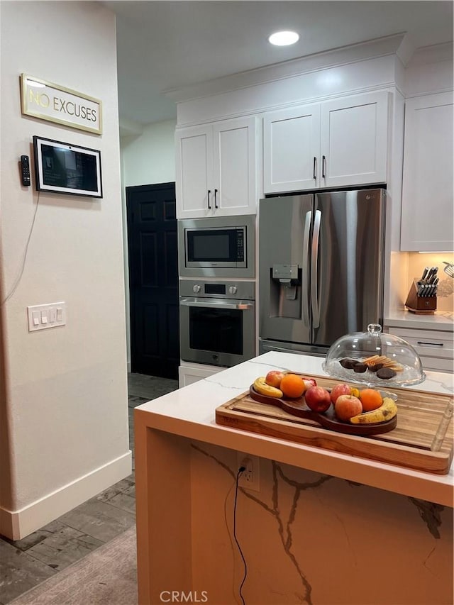 kitchen featuring stainless steel appliances, recessed lighting, white cabinets, wood finished floors, and baseboards