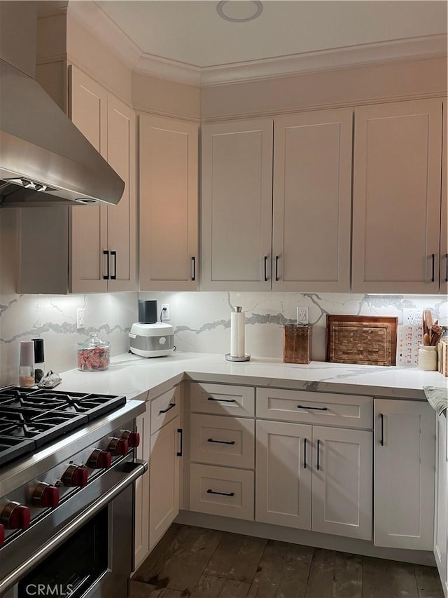 kitchen featuring white cabinets, light countertops, high end stainless steel range oven, decorative backsplash, and wall chimney exhaust hood