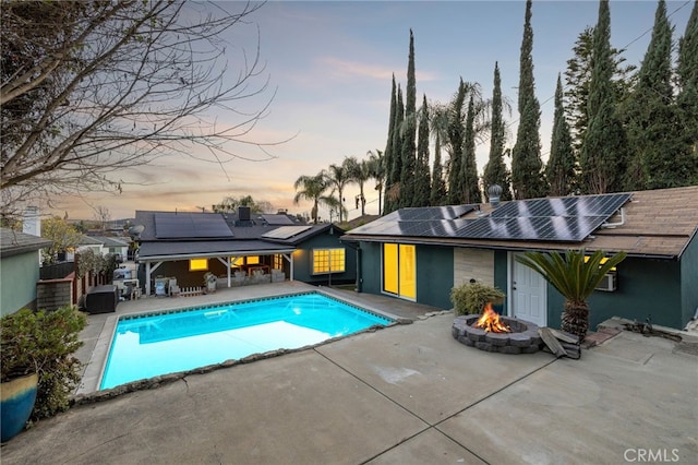 pool at dusk featuring a patio, an outdoor fire pit, fence, and an outdoor pool