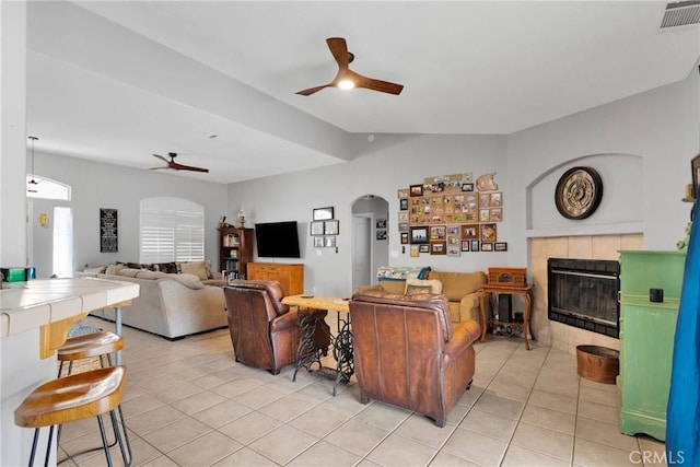 living area featuring arched walkways, ceiling fan, light tile patterned flooring, visible vents, and a tiled fireplace