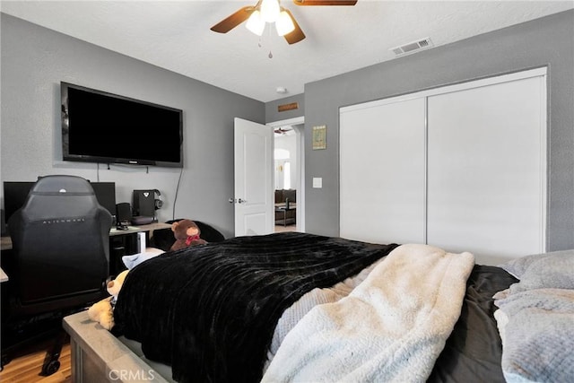 bedroom featuring light wood-style flooring, a closet, visible vents, and a ceiling fan