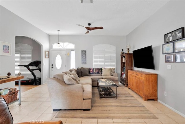 living room with arched walkways, light tile patterned flooring, ceiling fan, and visible vents