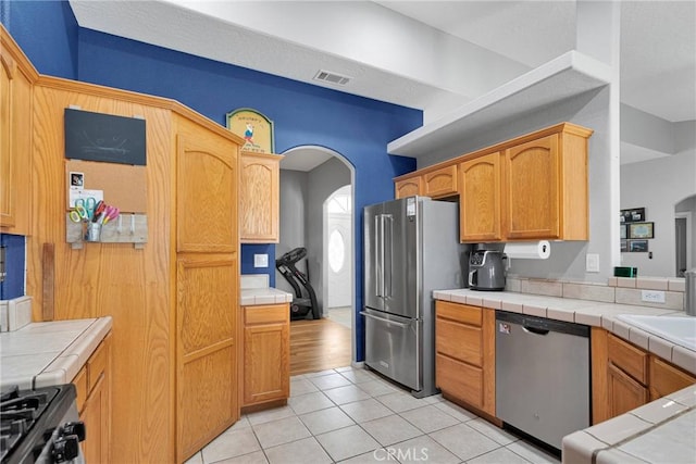 kitchen with visible vents, appliances with stainless steel finishes, arched walkways, and light tile patterned flooring