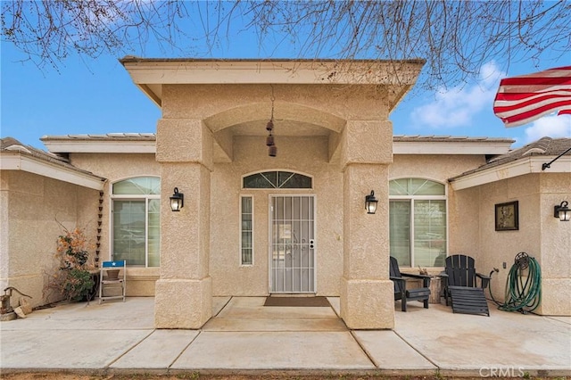 view of exterior entry featuring a patio and stucco siding