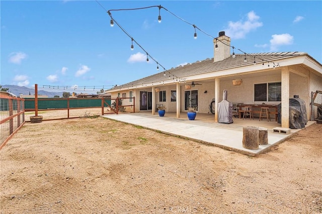 back of property featuring a chimney, stucco siding, a patio area, ceiling fan, and fence