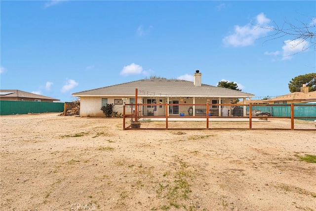 back of property with volleyball court, a chimney, and fence