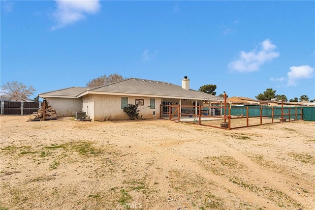 back of house featuring a tile roof, central AC, and stucco siding