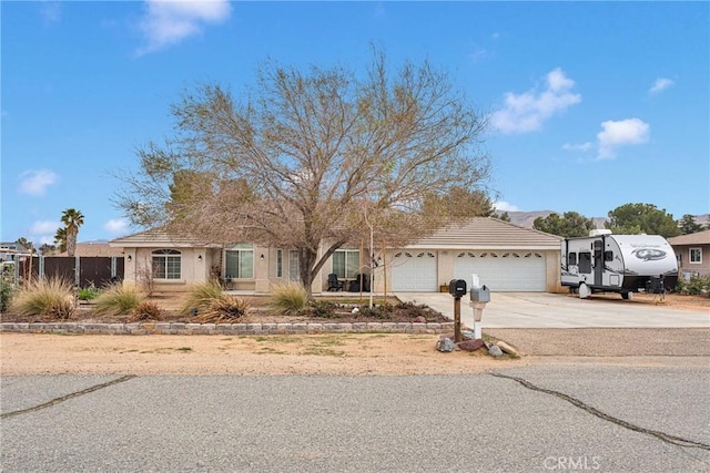 ranch-style home featuring a garage, concrete driveway, and stucco siding