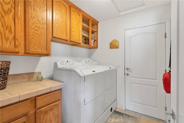 laundry room with light tile patterned floors, separate washer and dryer, and cabinet space