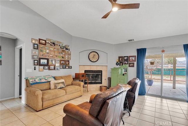 living area featuring light tile patterned floors, visible vents, arched walkways, a ceiling fan, and a fireplace