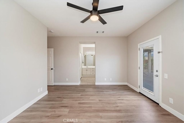 unfurnished bedroom featuring ensuite bathroom, light wood-style flooring, visible vents, baseboards, and access to exterior