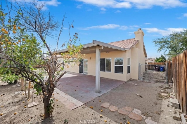 back of house featuring a tile roof, a patio, a chimney, stucco siding, and a fenced backyard