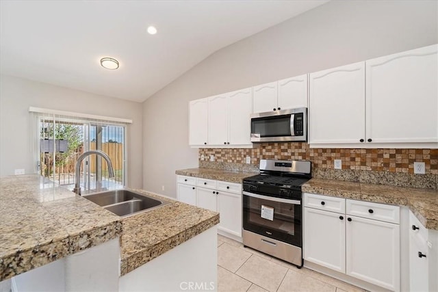 kitchen featuring tile countertops, lofted ceiling, decorative backsplash, appliances with stainless steel finishes, and a sink