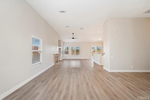 unfurnished living room featuring light wood finished floors, baseboards, visible vents, ceiling fan, and a fireplace