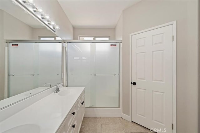 full bathroom with double vanity, a stall shower, tile patterned flooring, and a sink