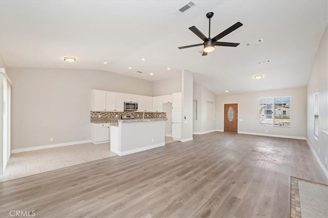 unfurnished living room featuring visible vents, light wood-style floors, a ceiling fan, vaulted ceiling, and baseboards