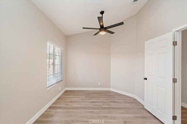 spare room featuring light wood finished floors, visible vents, vaulted ceiling, ceiling fan, and baseboards