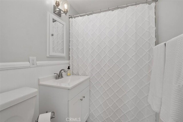 full bathroom with a wainscoted wall, vanity, and toilet