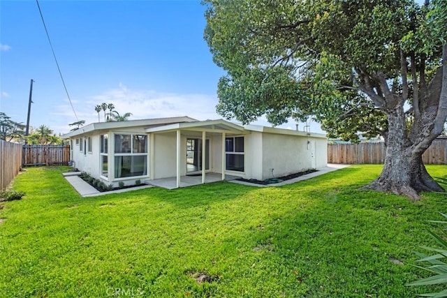 back of property with a fenced backyard, a patio, a lawn, and stucco siding