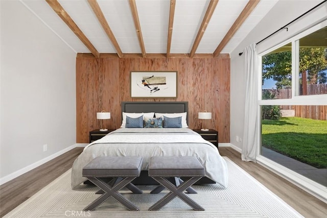 bedroom with baseboards, wood finished floors, beam ceiling, and wooden walls