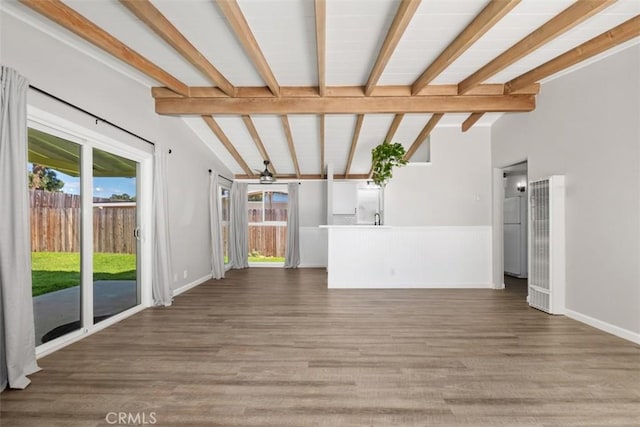 unfurnished living room featuring lofted ceiling with beams, baseboards, and wood finished floors