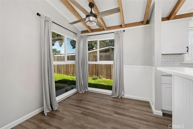 unfurnished dining area with baseboards, dark wood-style flooring, beam ceiling, and a healthy amount of sunlight