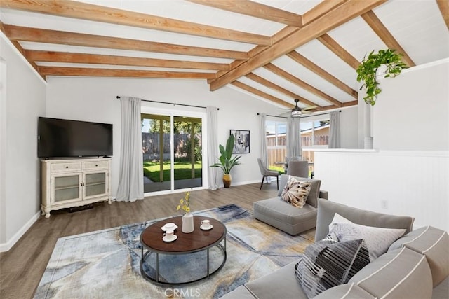 living area with a healthy amount of sunlight, lofted ceiling with beams, and wood finished floors