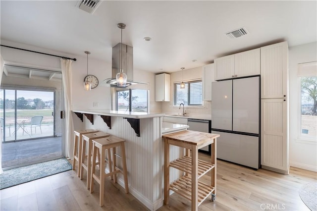 kitchen with stainless steel appliances, light wood-style flooring, a sink, and visible vents