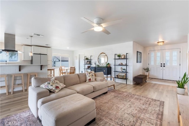 living area with light wood-type flooring, visible vents, and a ceiling fan