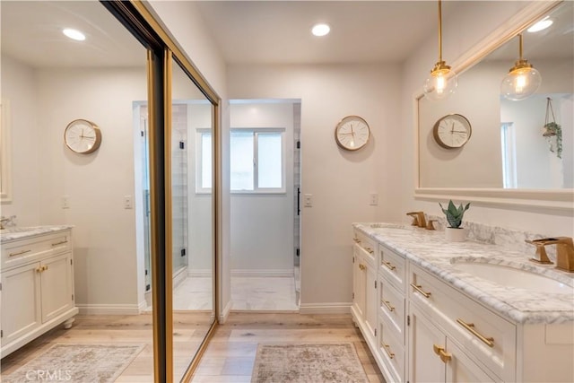 bathroom with double vanity, recessed lighting, a sink, wood finished floors, and baseboards