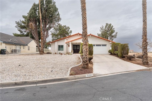 view of front of home with a garage, driveway, fence, and stucco siding