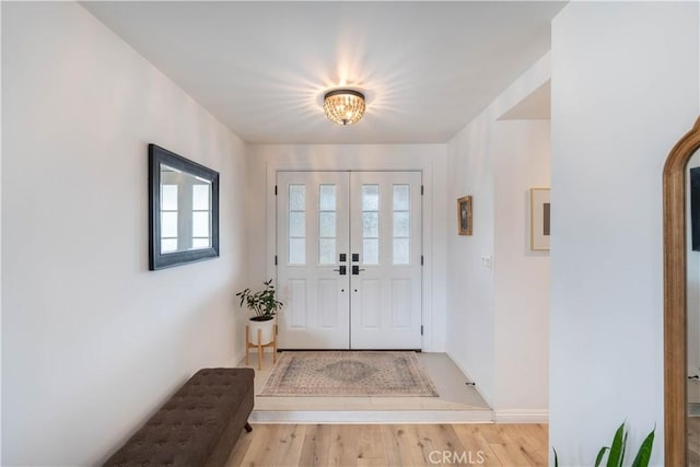 foyer entrance with light wood-style flooring and baseboards