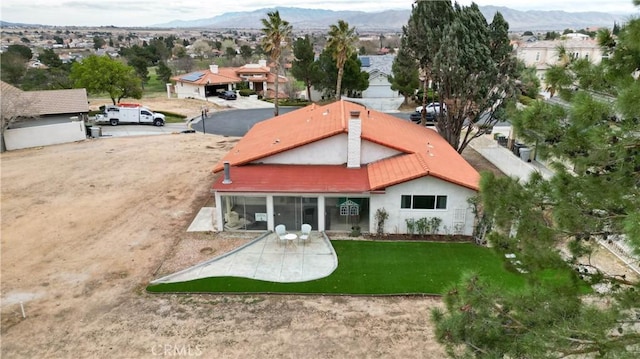 rear view of house featuring stucco siding, a mountain view, and a yard