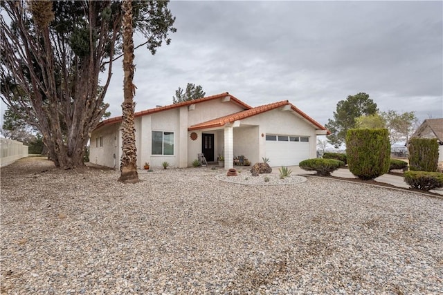 view of front of house featuring concrete driveway, an attached garage, fence, and stucco siding