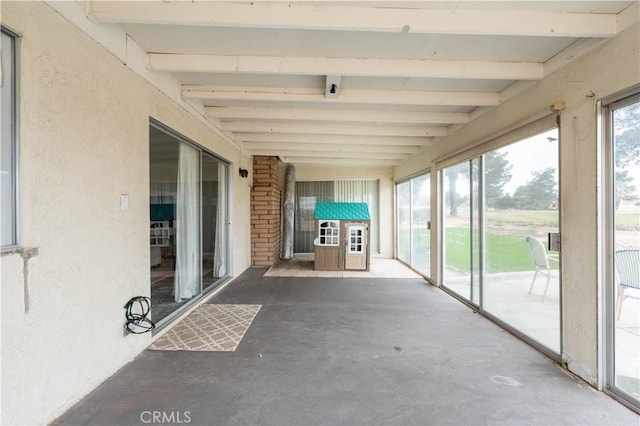 unfurnished sunroom featuring beam ceiling