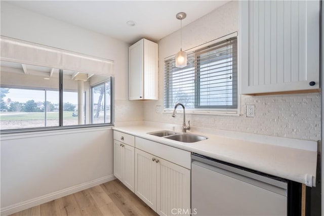 kitchen featuring dishwasher, tasteful backsplash, light wood-type flooring, and a sink