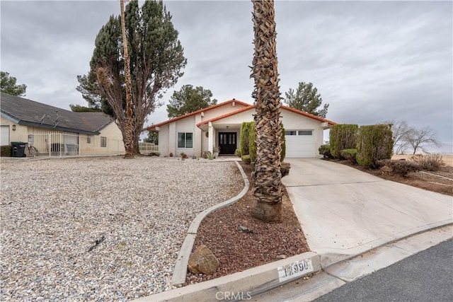 view of front of home with concrete driveway, fence, an attached garage, and stucco siding