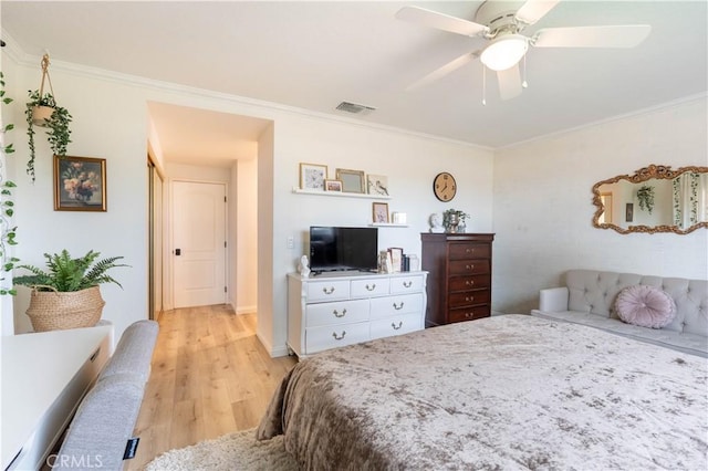 bedroom with light wood-style flooring, visible vents, and ornamental molding