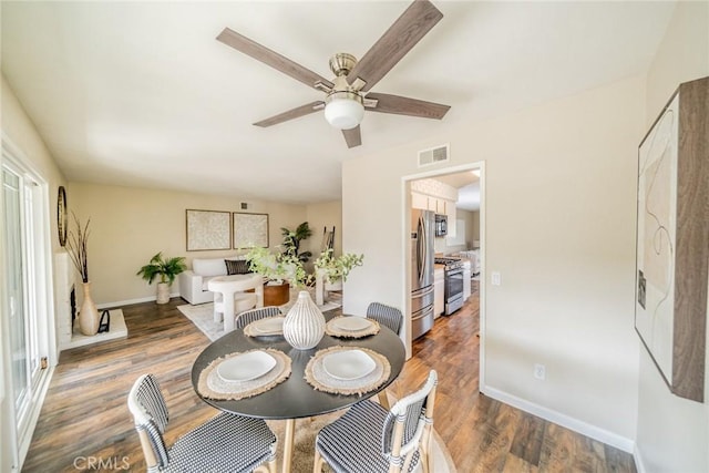 dining space featuring visible vents, baseboards, wood finished floors, and a ceiling fan