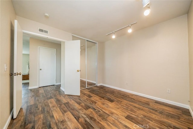 unfurnished bedroom featuring wood finished floors, visible vents, and baseboards