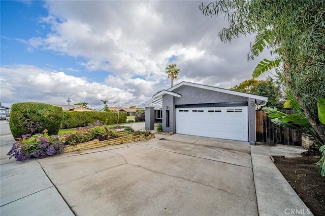 view of side of property featuring concrete driveway, fence, a garage, and stucco siding