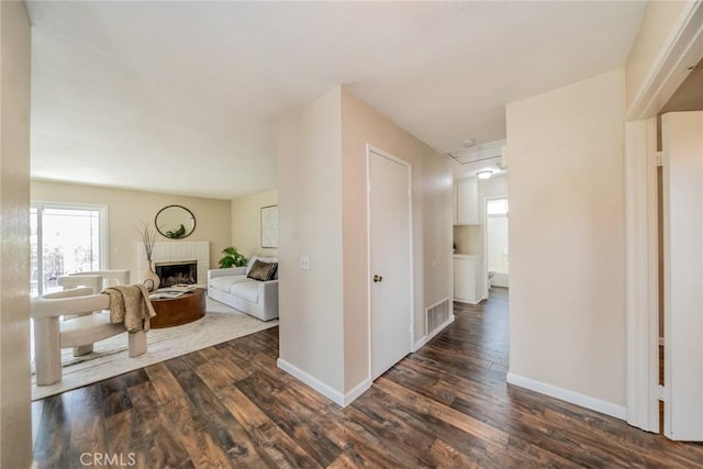 hallway featuring dark wood-type flooring, baseboards, and visible vents