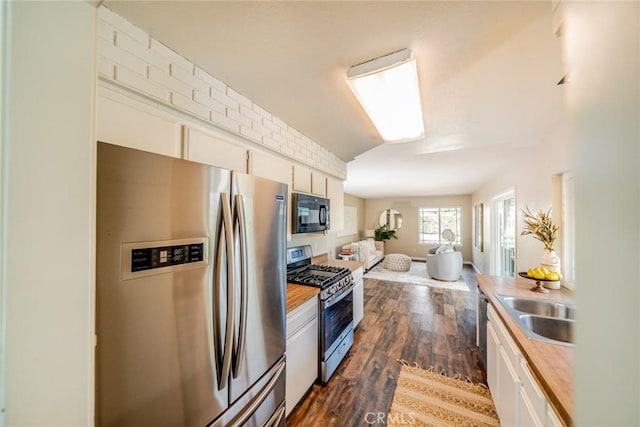 kitchen featuring butcher block countertops, open floor plan, dark wood finished floors, stainless steel appliances, and white cabinets